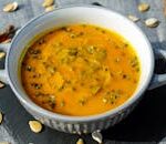 Warm and creamy pumpkin soup garnished with fresh herbs, perfect for a cozy meal.
